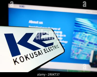 Mobile phone with logo of Japanese company Kokusai Electric Corporation on screen in front of business website. Focus on center of phone display. Stock Photo