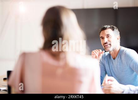 Mature businessman talking to colleague during meeting Stock Photo