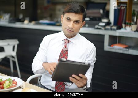Businessman holding tablet PC at restaurant Stock Photo