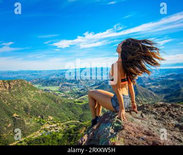 Young woman sitting on mountain rock Stock Photo