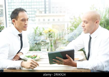 Businessmen using tablet PC during restaurant meeting Stock Photo