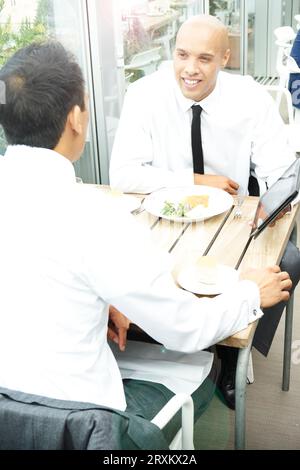 Businessmen using tablet PC during restaurant meeting Stock Photo