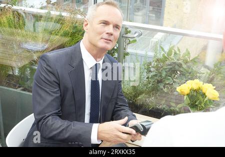 Businessman using EFTPOS machine at restaurant table Stock Photo
