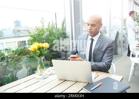 Businessman using smartphone and laptop in restaurant Stock Photo