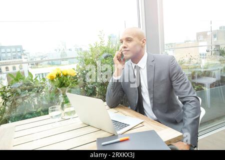Businessman using smartphone and laptop in restaurant Stock Photo