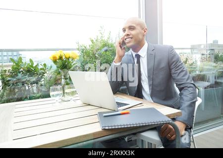 Businessman using smartphone and laptop in restaurant Stock Photo