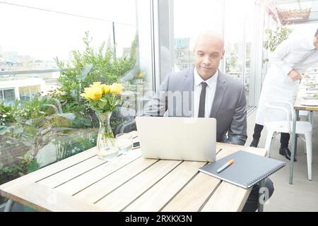 Businessman using laptop at restaurant table Stock Photo