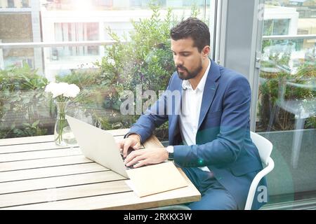 Businessman using laptop at restaurant table Stock Photo