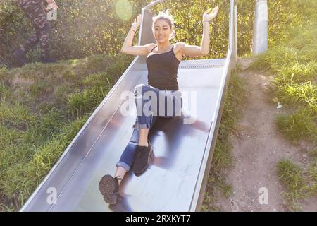 Young woman playing on slide Stock Photo