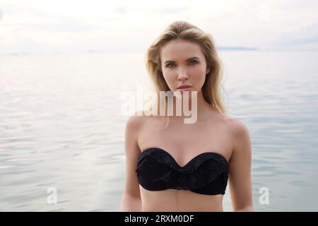 Young woman wearing black bikini standing in sea Stock Photo