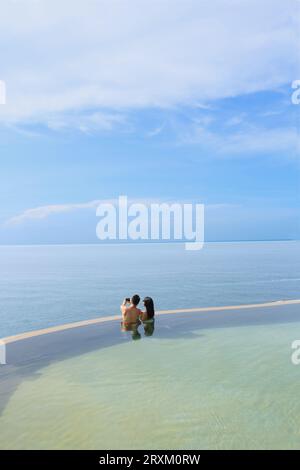 Young couple taking selfie in swimming pool by sea Stock Photo
