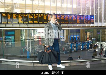 Senior man using mobile phone in train station Stock Photo