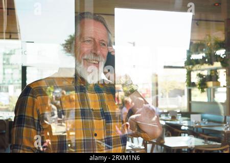 Senior man on phone call behind window Stock Photo