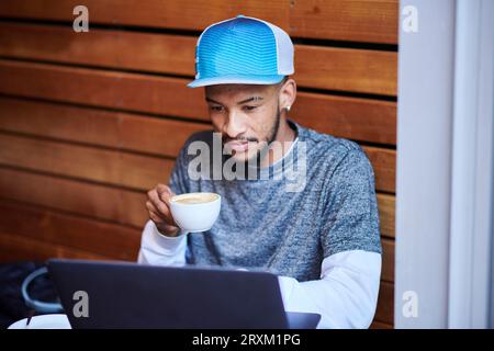 Young man with laptop drinking coffee Stock Photo