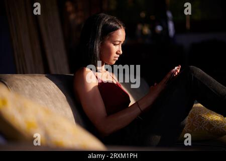 Young woman using smart phone on sofa Stock Photo