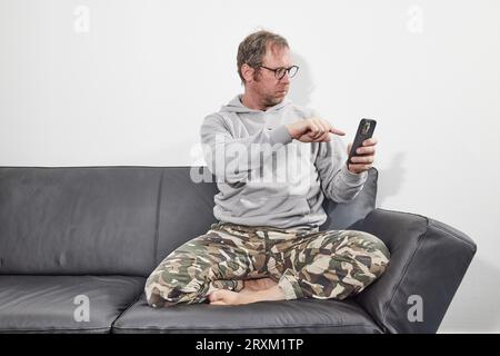 Man with glasses at home using mobile smart phone Stock Photo