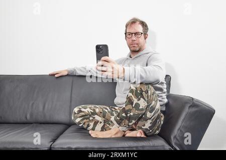 Man with glasses at home using mobile smart phone Stock Photo
