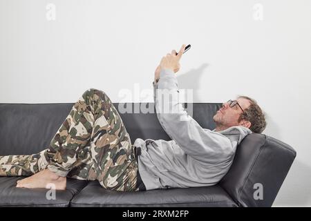 Man with glasses at home using mobile smart phone Stock Photo