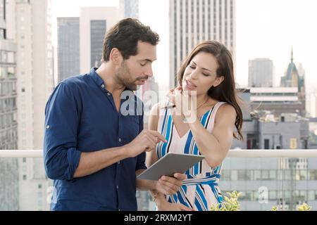Young couple with tablet PC on balcony in New York City Stock Photo