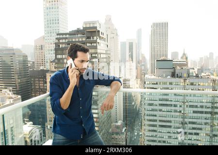 Young man using smart phone on balcony in New York City Stock Photo