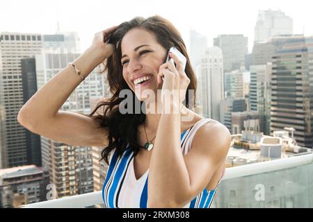 Young woman using smartphone on balcony in New York City Stock Photo