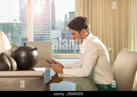 Young man using smartphone at table in New York City Stock Photo