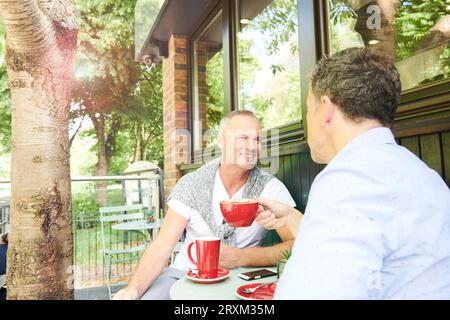 Gay couple with drinks on balcony Stock Photo