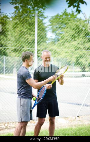 Gay couple holding tennis rackets and balls Stock Photo