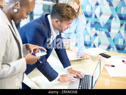 Businesspeople using smart phone and laptop in meeting Stock Photo