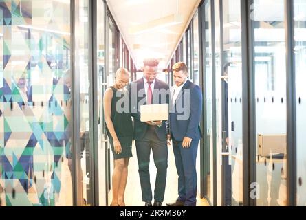 Businesspeople using laptop in office corridor Stock Photo