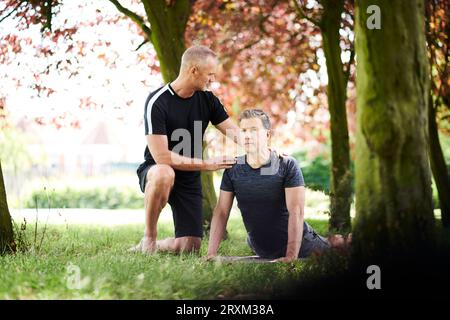 Mature men practicing yoga in park Stock Photo