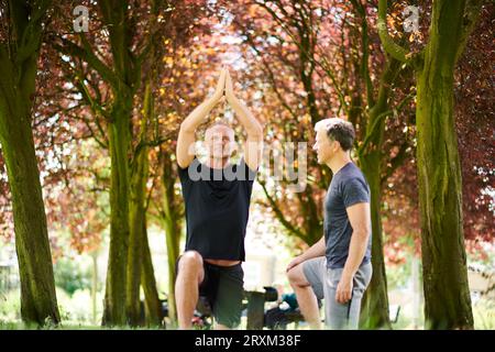 Mature men practicing yoga in park Stock Photo