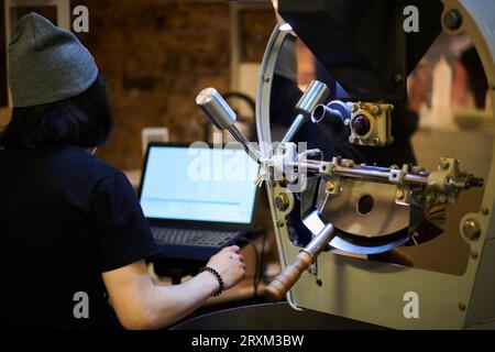 Man using laptop by machinery Stock Photo