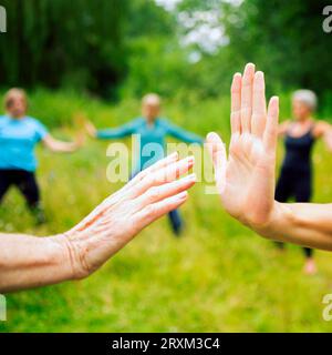 Women touching hands during exercise class Stock Photo