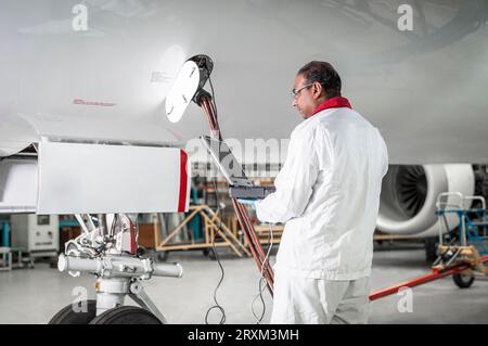 Man using laptop by airplane in hangar Stock Photo