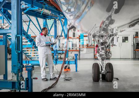 Man using laptop by airplane in hangar Stock Photo