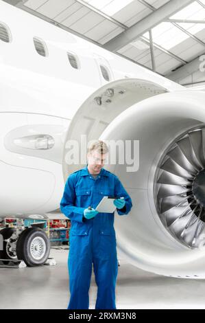 Young man using digital tablet by airplane engine Stock Photo