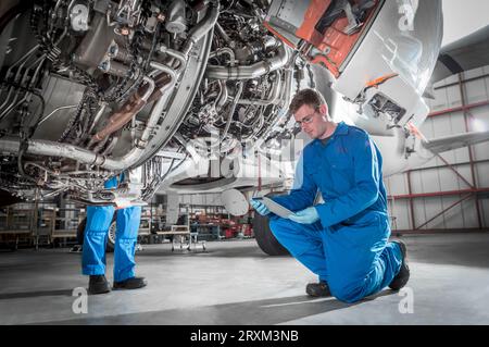 Crouched man using digital table by airplane Stock Photo