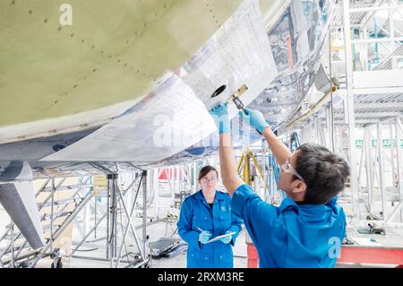 Man working on airplane with woman holding digital tablet Stock Photo