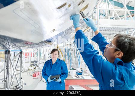 Man working on airplane with woman holding digital tablet Stock Photo