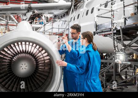 Man and woman working on airplane engine Stock Photo