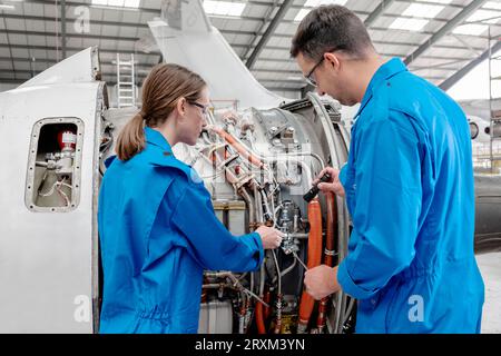 Man and woman working on airplane engine Stock Photo