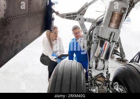 Workers using digital tablet by airplane wheel Stock Photo