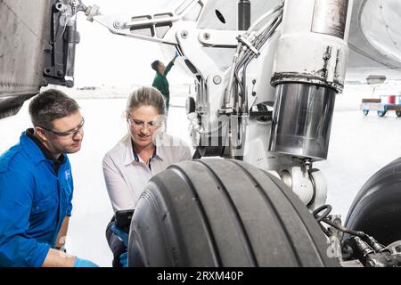 Workers crouched by airplane wheel Stock Photo