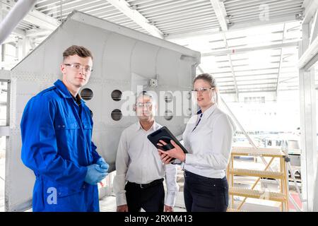 Workers with digital tablet in airplane hangar Stock Photo