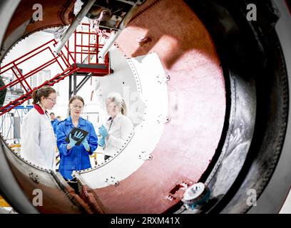 Female workers using digital tablet behind airplane engine Stock Photo