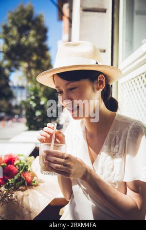 Young woman wearing straw hat holding iced coffee Stock Photo