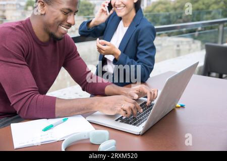 Smiling young man using laptop on balcony Stock Photo