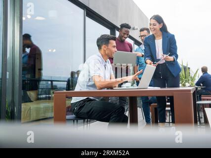 Colleagues using laptops on balcony Stock Photo