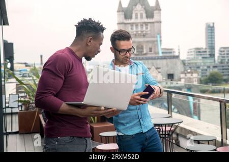 Businessmen using laptop and smart phone on balcony Stock Photo